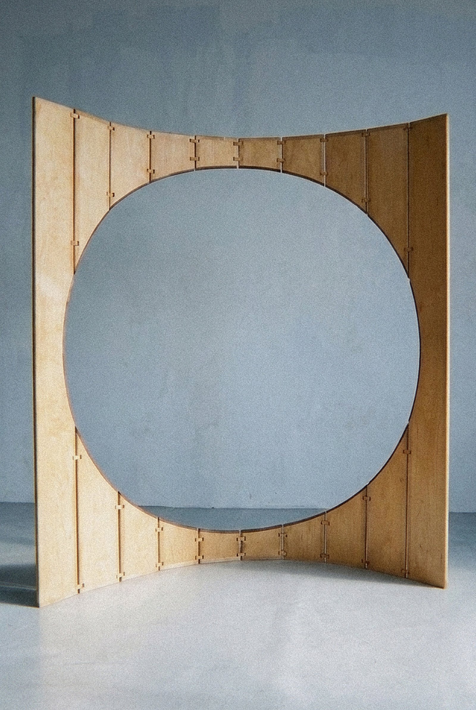 Vista aproximada da escultura móvel Ó disposta em curva aberta com ampla abertura circular vazada.