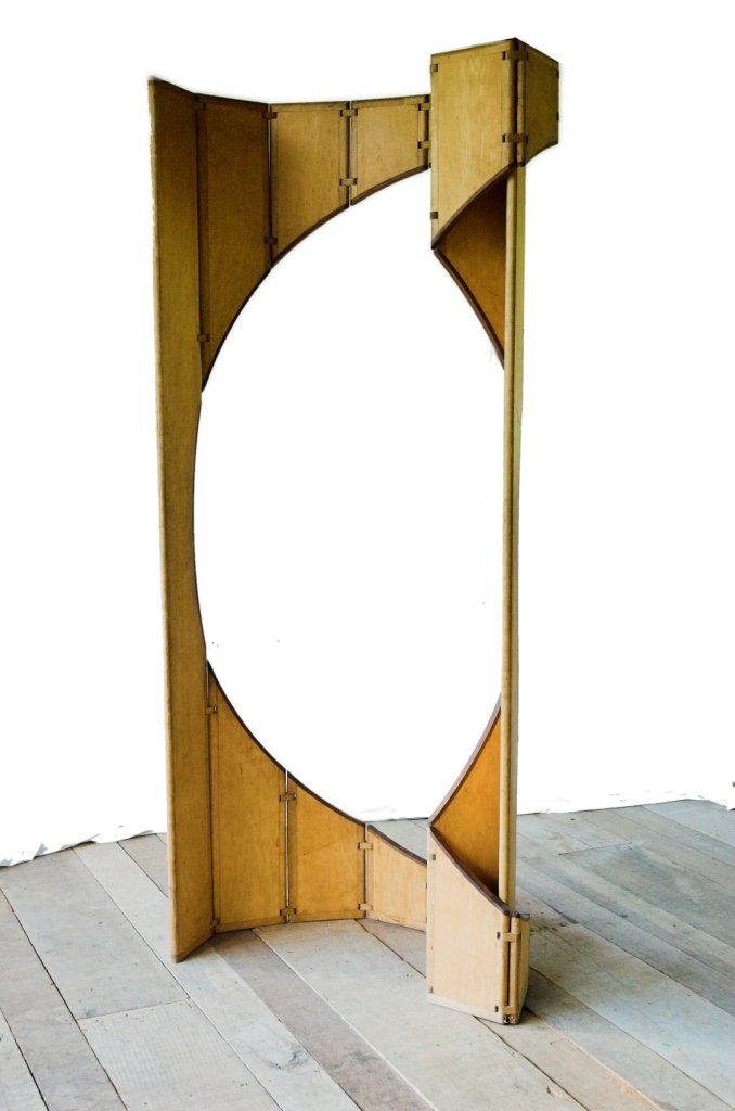 A escultura móvel Ó aberta em curva com grande abertura oval recortada entre painéis de madeira de maple.