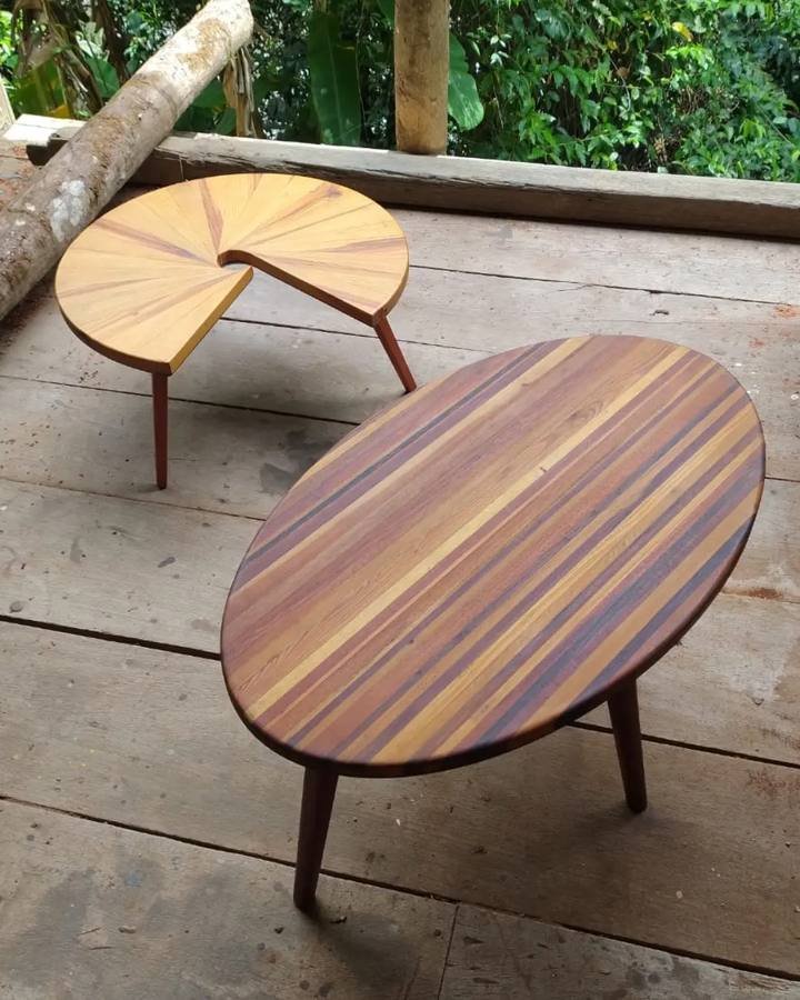 Mesa Caracol de madeira de recuperação disposta sobre tábuas de madeira ao lado de uma mesa oval ripada.