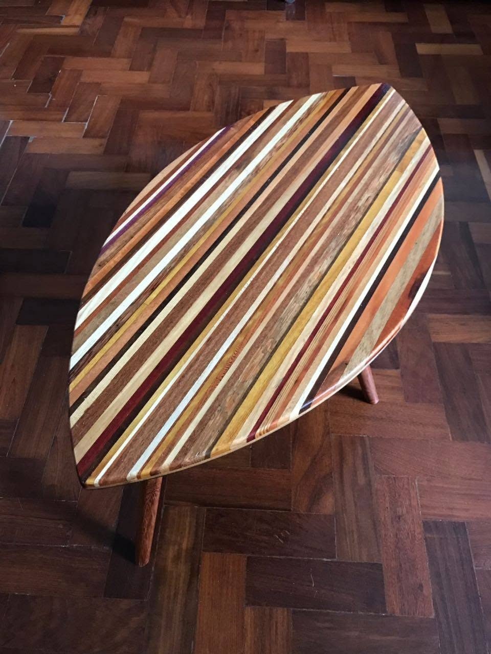 Vista superior da Mesa Folha em forma de folha sobre piso de tacos de madeira.