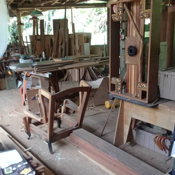 Workshop interior showing an unfinished wooden chair frame and a sculptural box on a bench.