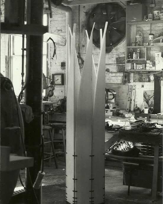 Tall standing mobile sculpture with pointed wood panels standing assembled in a studio.
