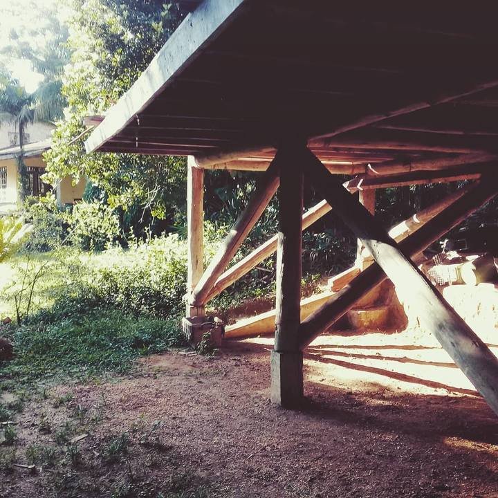 Space beneath the workshop platform showing heavy diagonal timber posts and dirt ground.