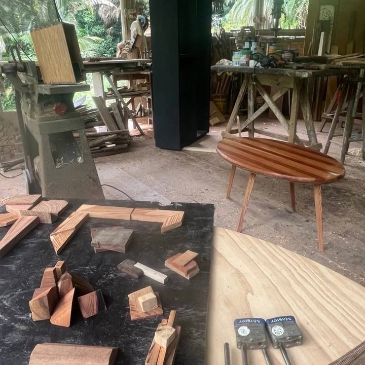Woodworking workshop with cut blocks of wood, machinery, and a small oval wooden table.