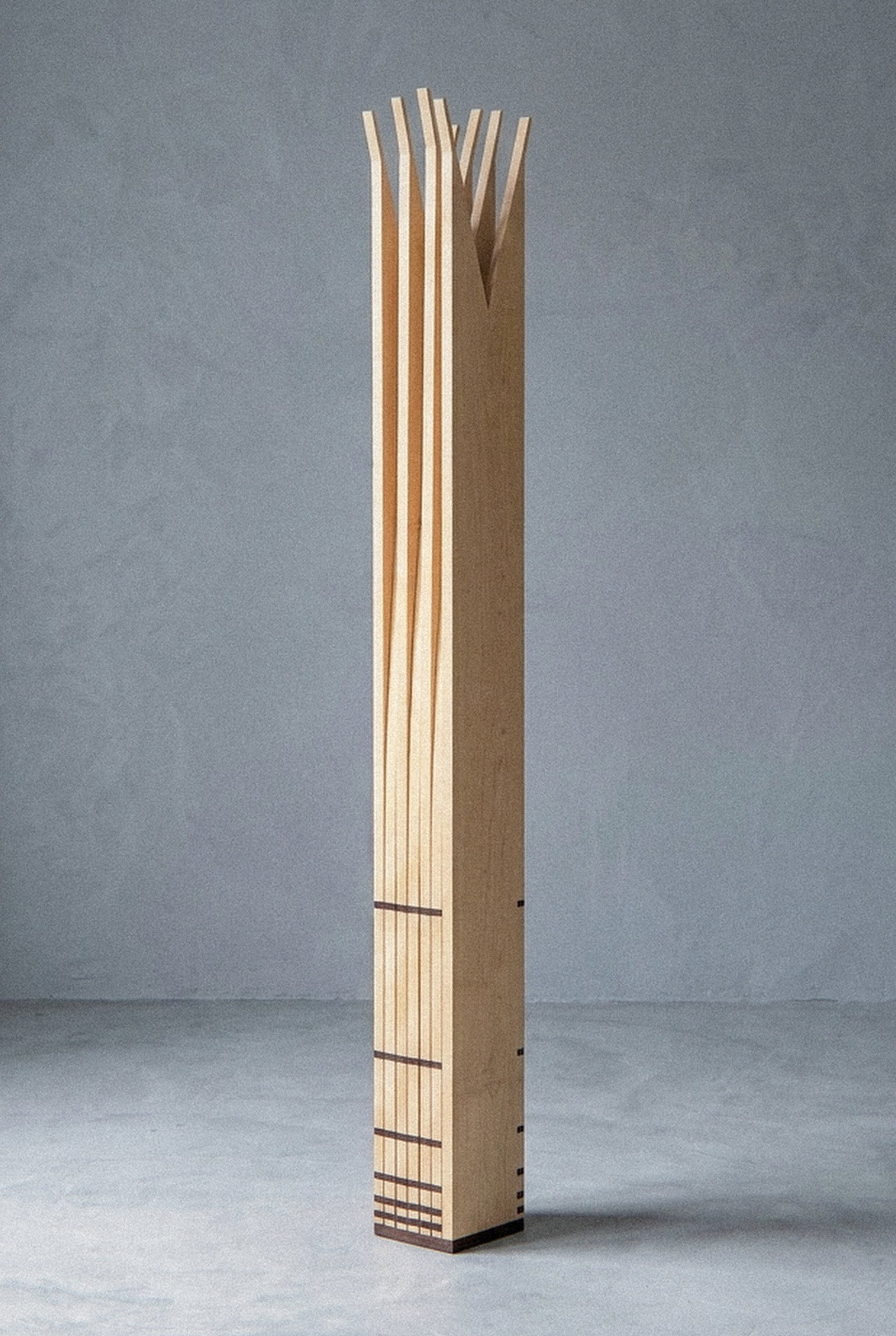 A escultura móvel Velas vista de perto, fechada em coluna vertical reta com encaixes escuros na base.