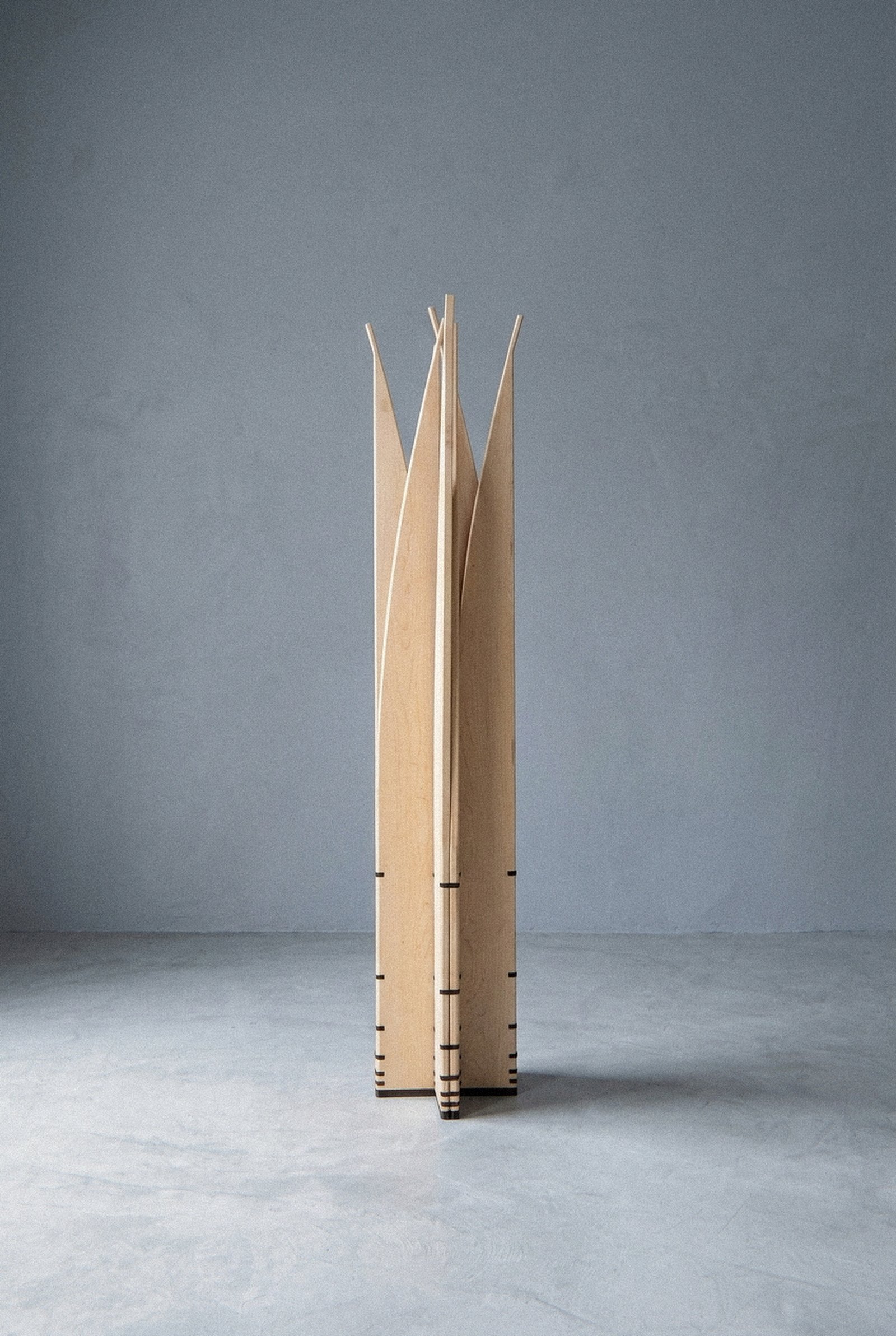 A escultura móvel Velas vista inteira à distância, aberta em estreita coluna radial com lâminas pontiagudas voltadas para fora.